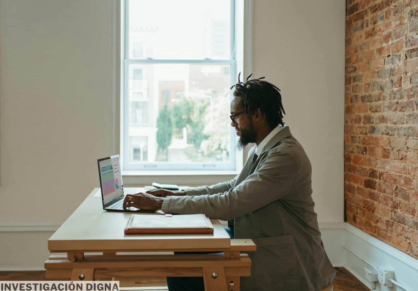 a person sitting at a desk with a laptop and papers