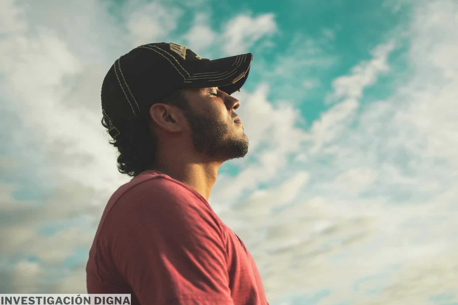 Man Wearing Black Cap With Eyes Closed Under Cloudy Sky