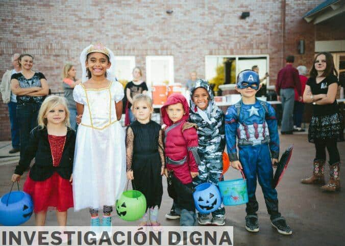 children standing while holding Jack 'o lantern and wearing costume