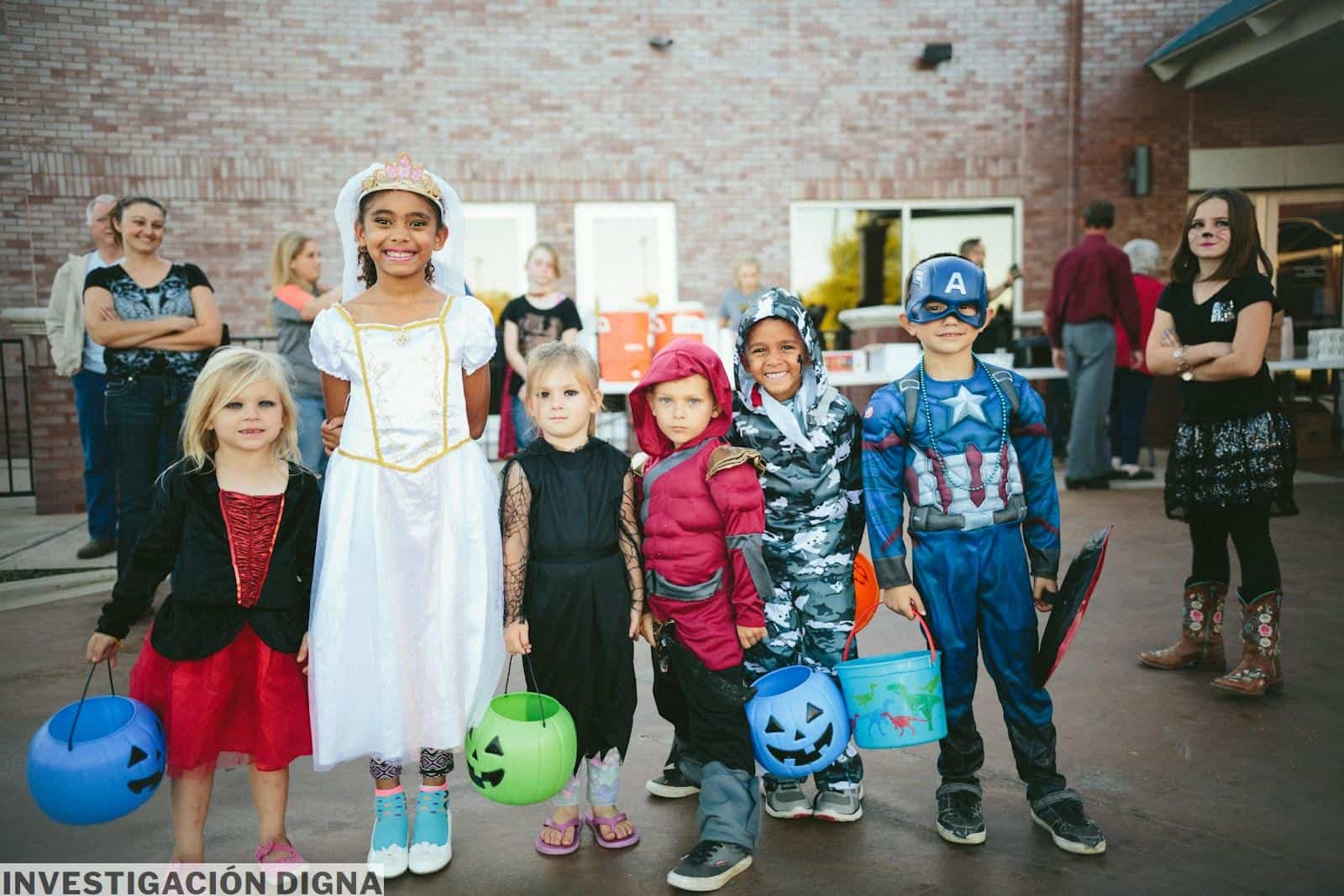 children standing while holding Jack 'o lantern and wearing costume