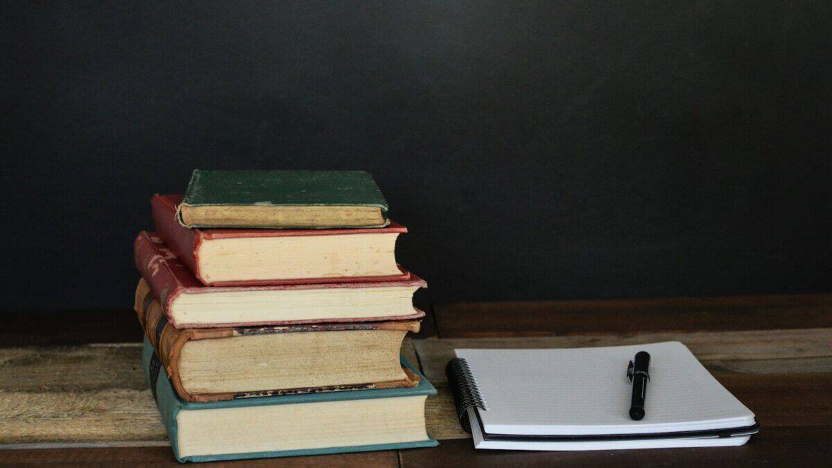 Pila de libros y un cuaderno abierto, el material de trabajo de la redacción de Investigación Digna