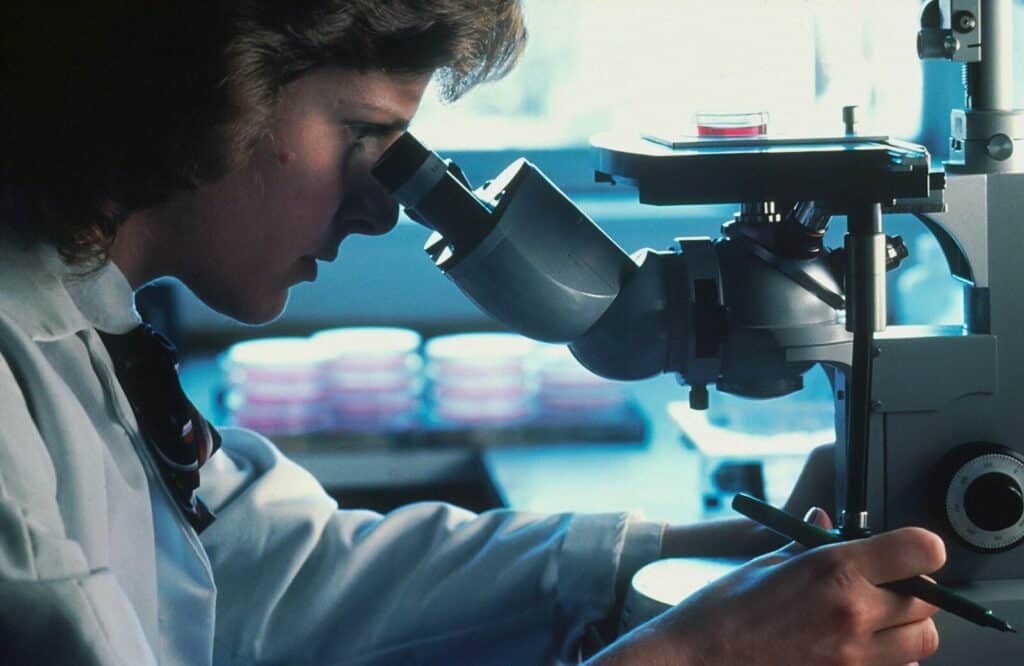 Investigadora observando una muestra al microscopio durante la fase de experimentación del método científico